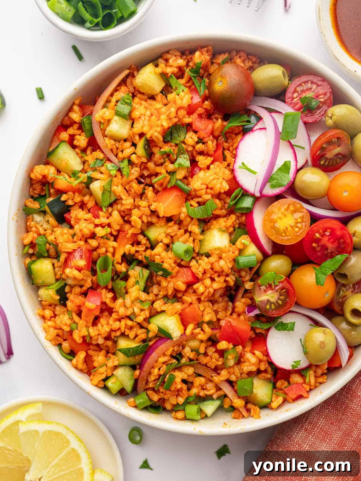 Turkish Bulgur Salad (Kisir) A large, inviting bowl of Turkish Kisir salad, garnished generously with fresh tomatoes, olives, and crisp radishes, ready to be served. The vibrant colors highlight the freshness of the ingredients.