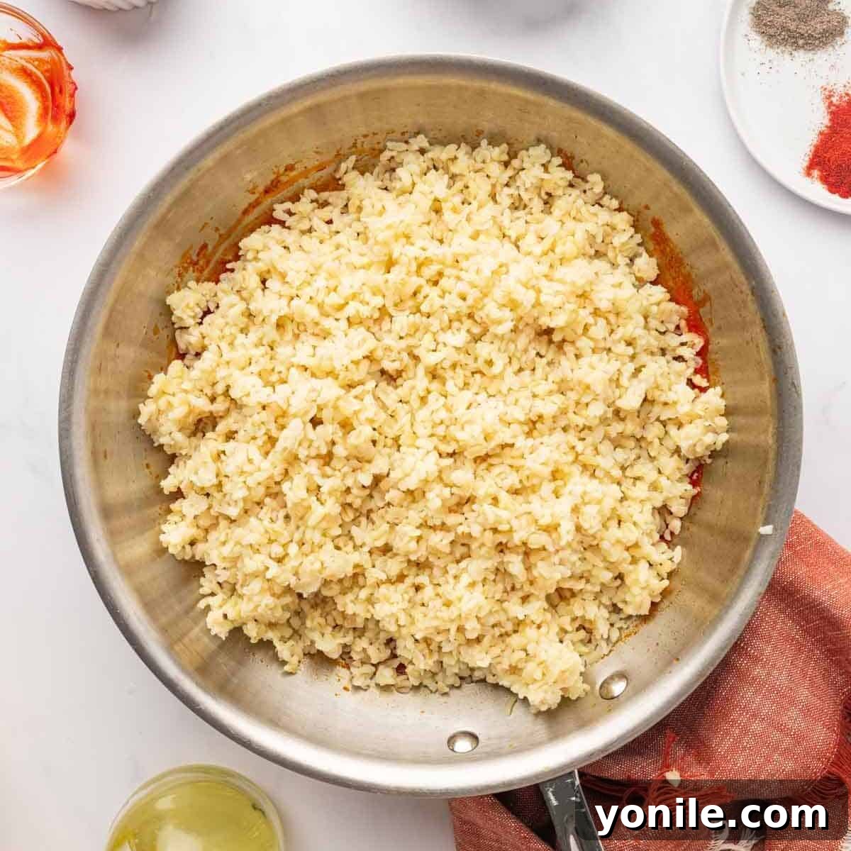 Vibrant Turkish Kisir Salad 8 The fluffy, cooked bulgur wheat carefully added on top of the vibrant tomato and red pepper paste mixture in a pan, before mixing.