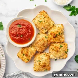 A platter of air fried ravioli with marinara sauce for dipping.