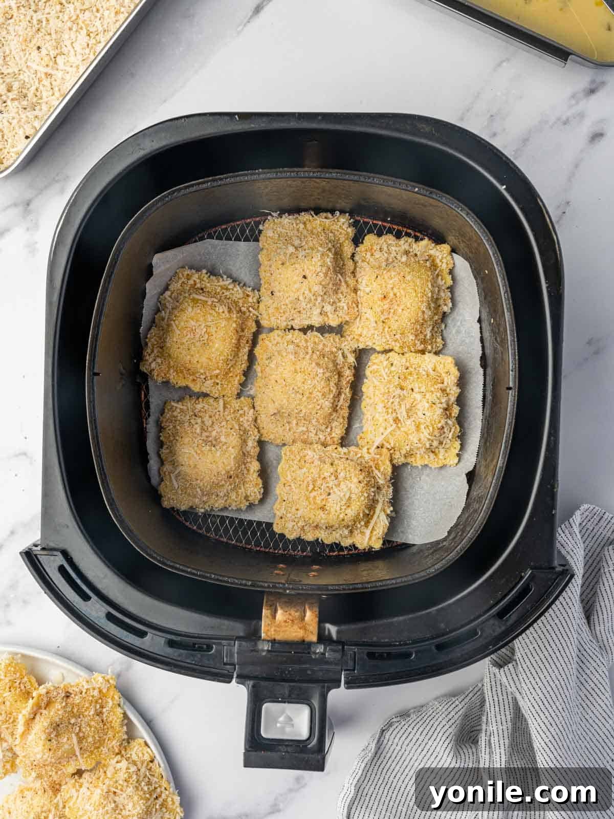 Crispy Air Fryer Ravioli 7 Breaded ravioli are in the air fryer basket in a single layer.