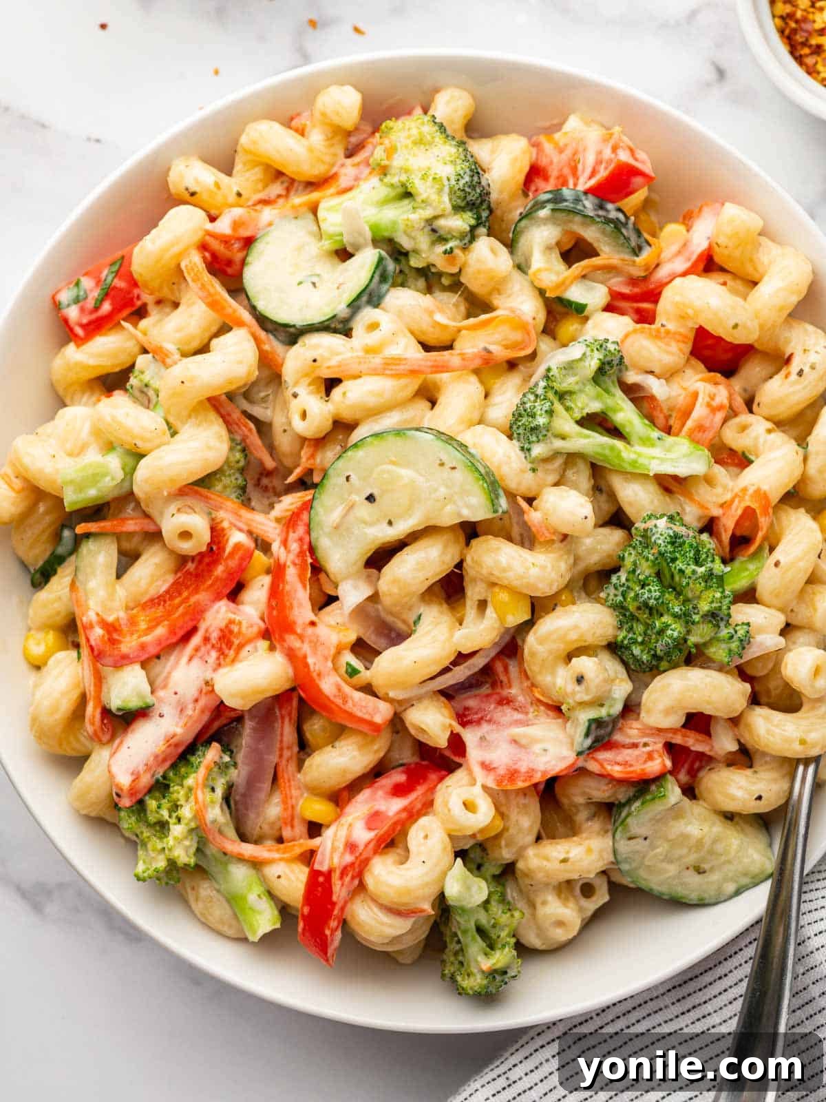 Closeup of a plate of creamy vegetable pasta, highlighting the textures and vibrant colors.