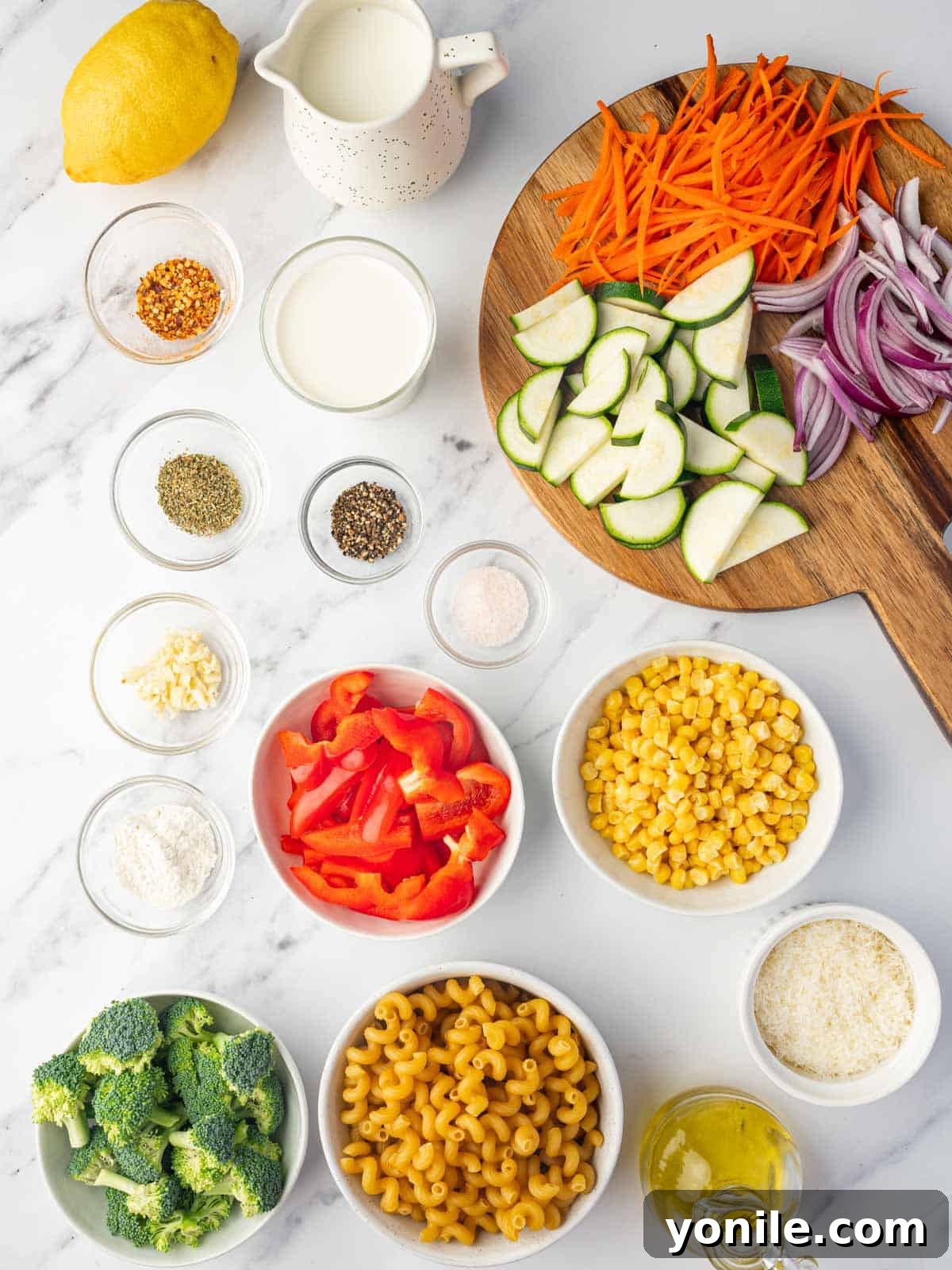 Ingredients needed for creamy veggie pasta, neatly arranged on a counter.