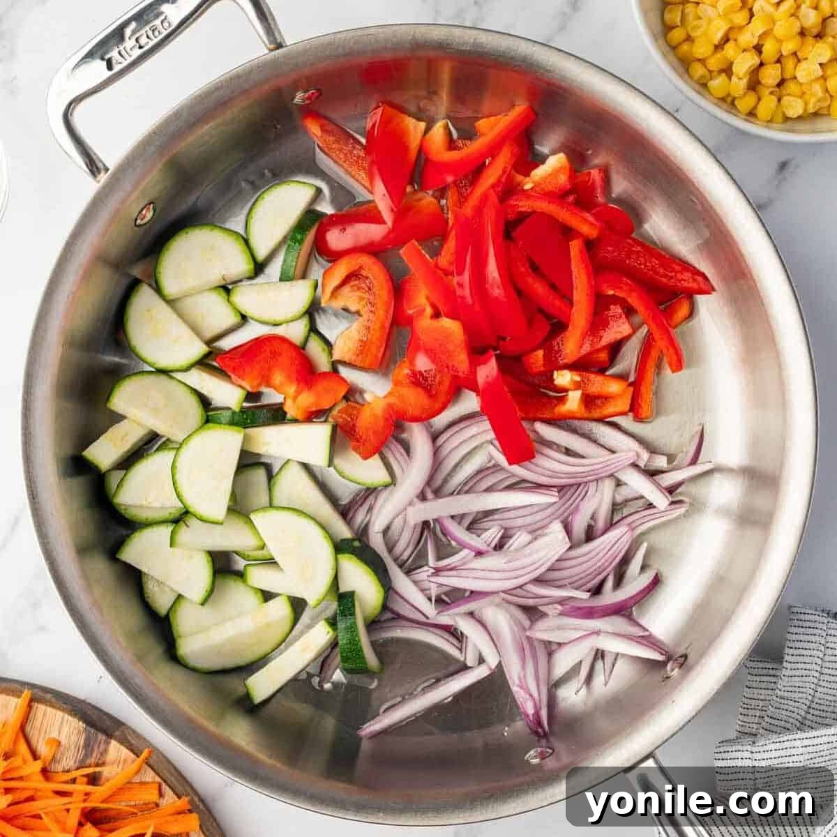 Chopped vegetables (onion, bell pepper, zucchini) are added to a skillet to saute in olive oil.