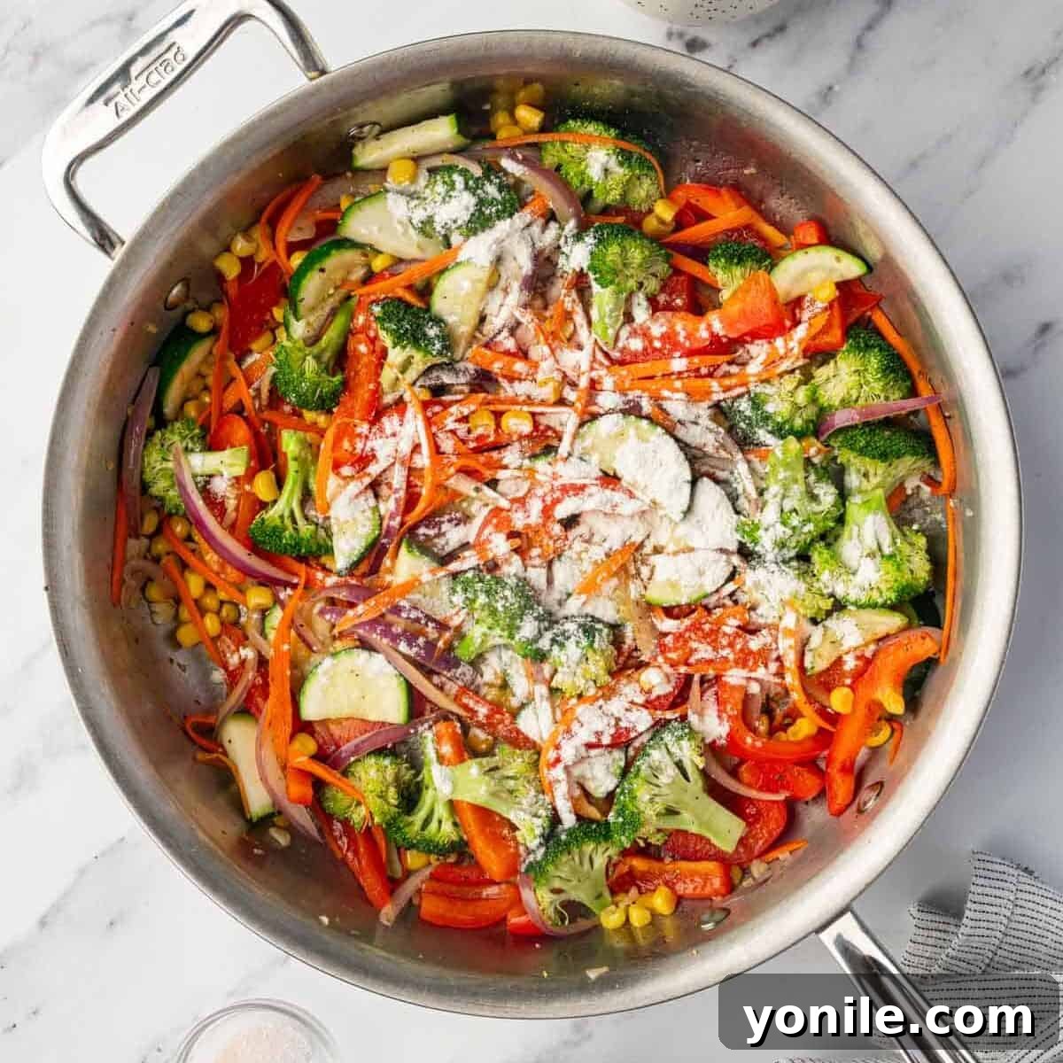 Flour is sprinkled over the sautéed vegetables in the skillet to prepare the sauce base.