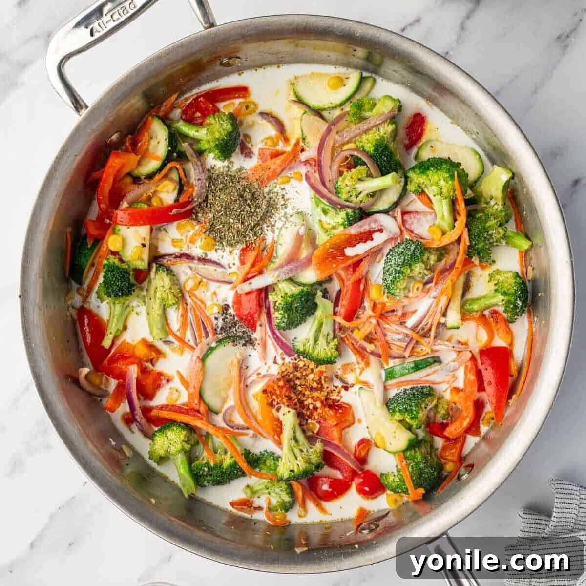 Heavy cream, milk, and seasonings are added to the creamy sauce blend in the skillet.