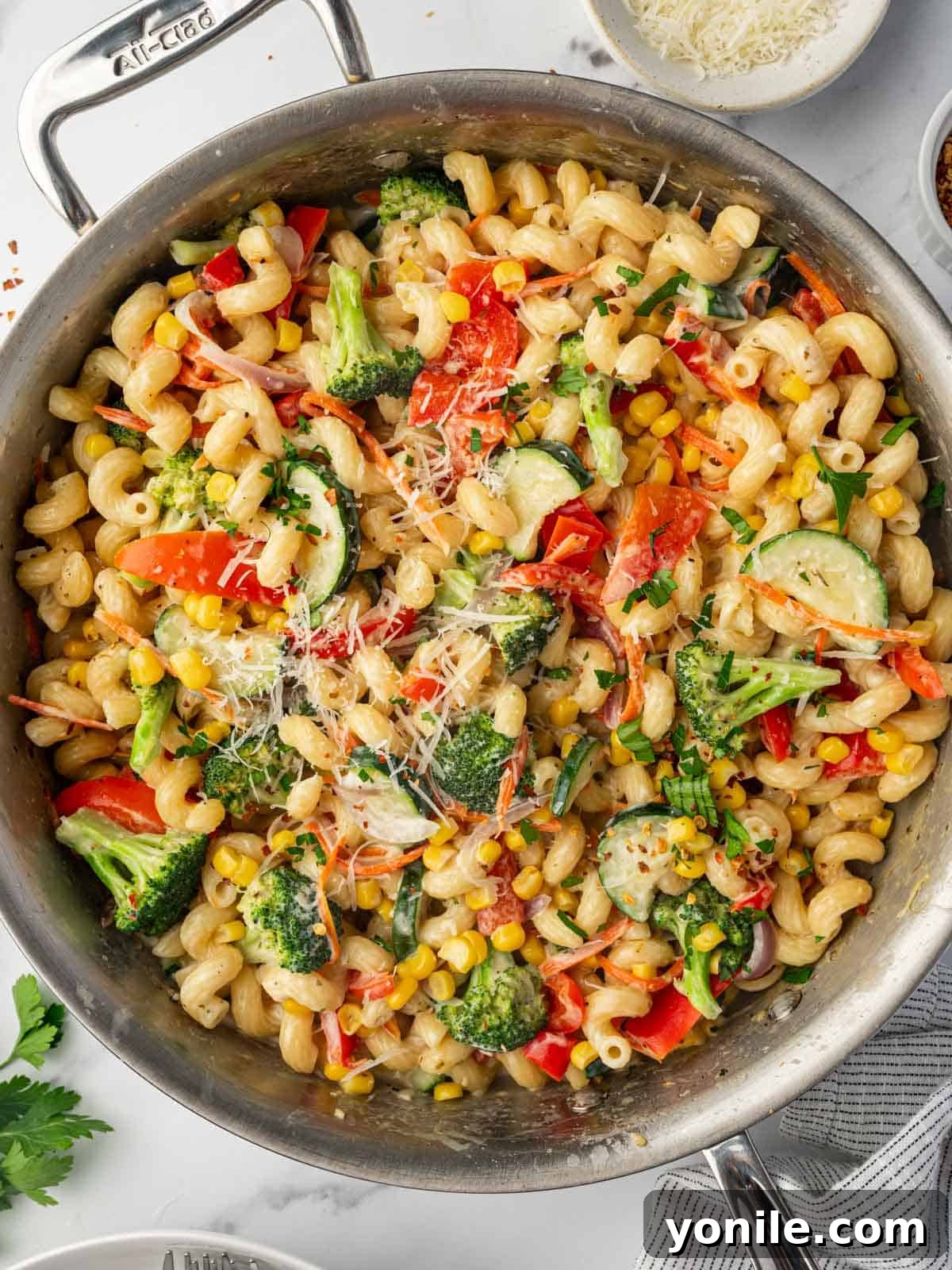 Parmesan cheese is sprinkled over the creamy veggie pasta, ready for serving.