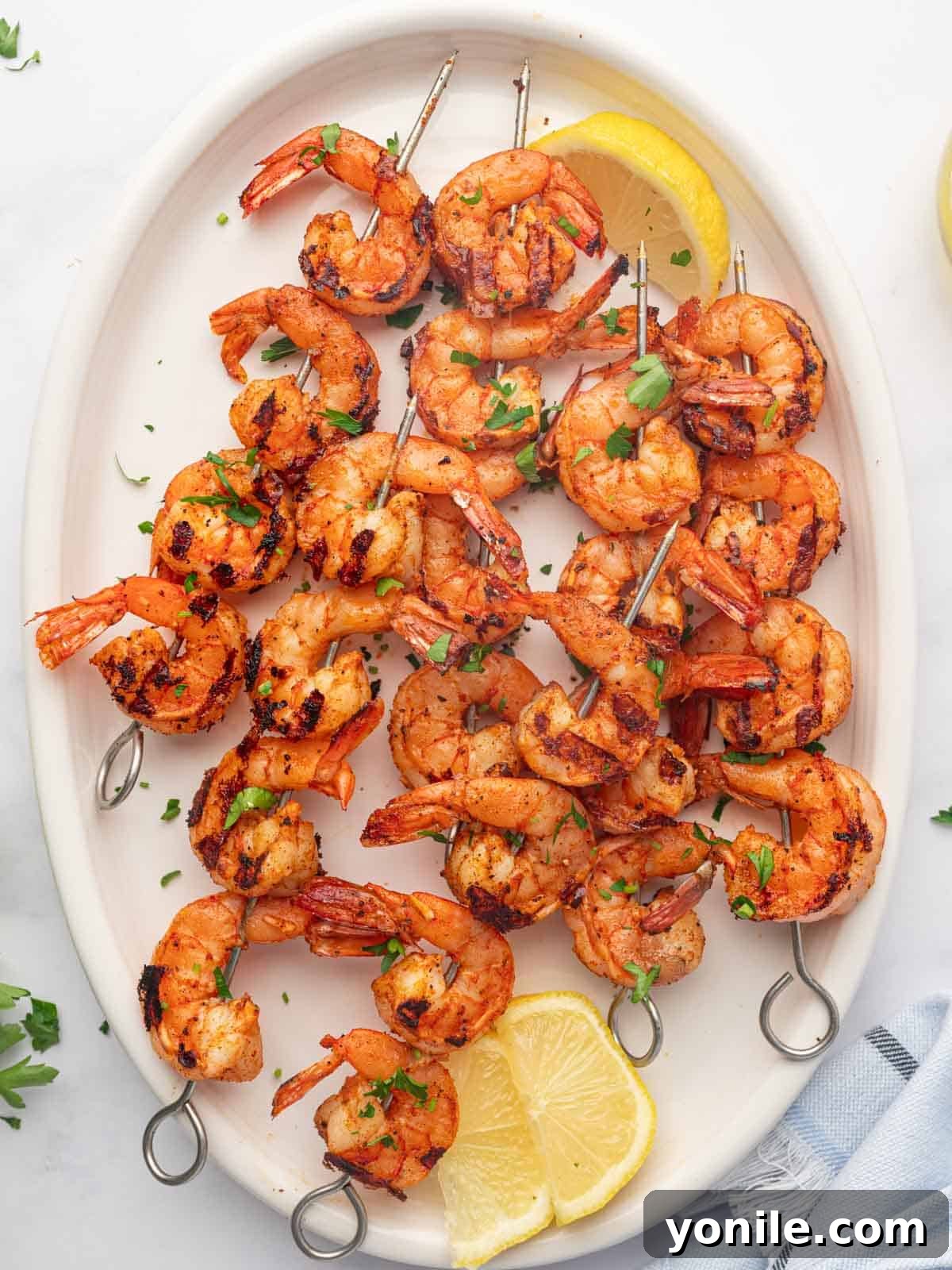 A platter with lemon wedges and perfectly grilled Cajun shrimp skewers, ready to serve.