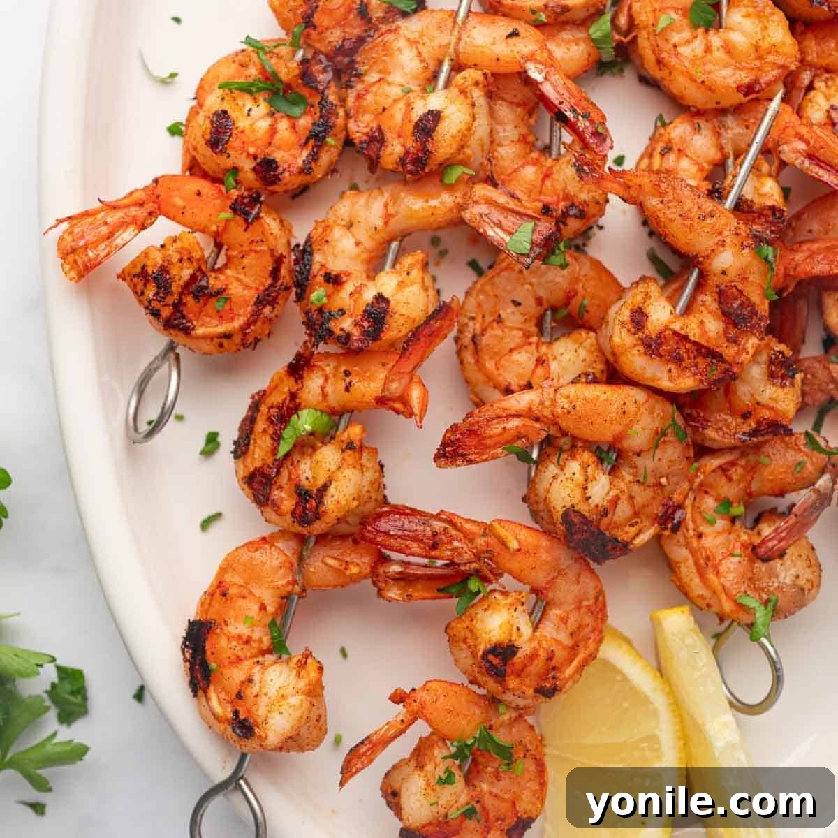 Grilled cajun shrimp skewers arranged on a platter with fresh lemon wedges.