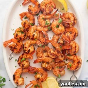 A platter with lemon wedges and grilled cajun shrimp skewers.