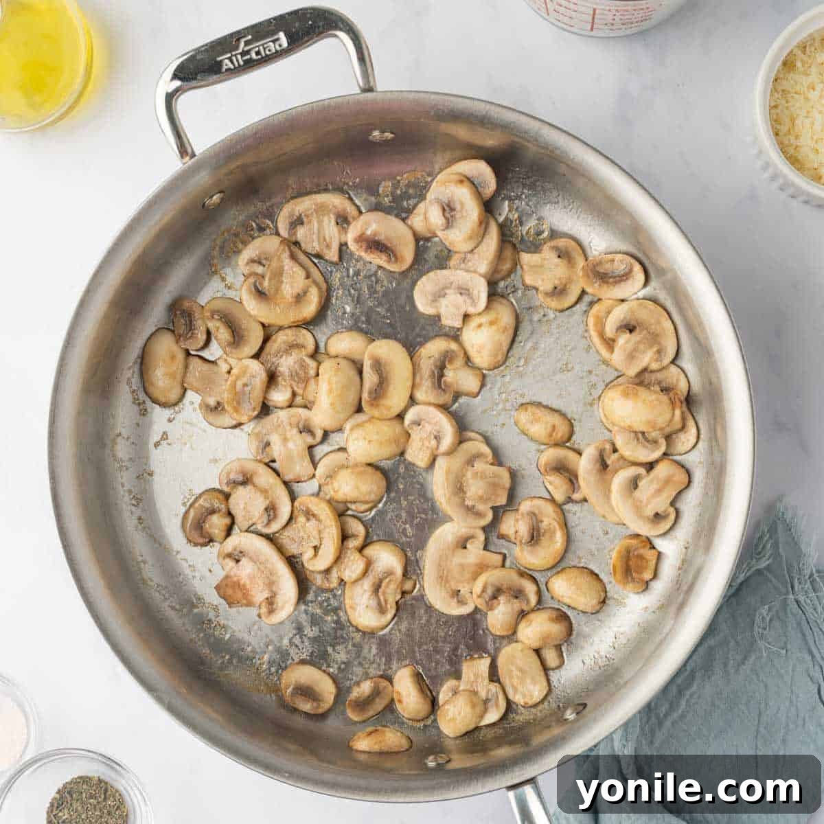 Creamy Cheese Tortellini Alfredo 4 Mushrooms being sautéed until golden brown in a large skillet with olive oil.