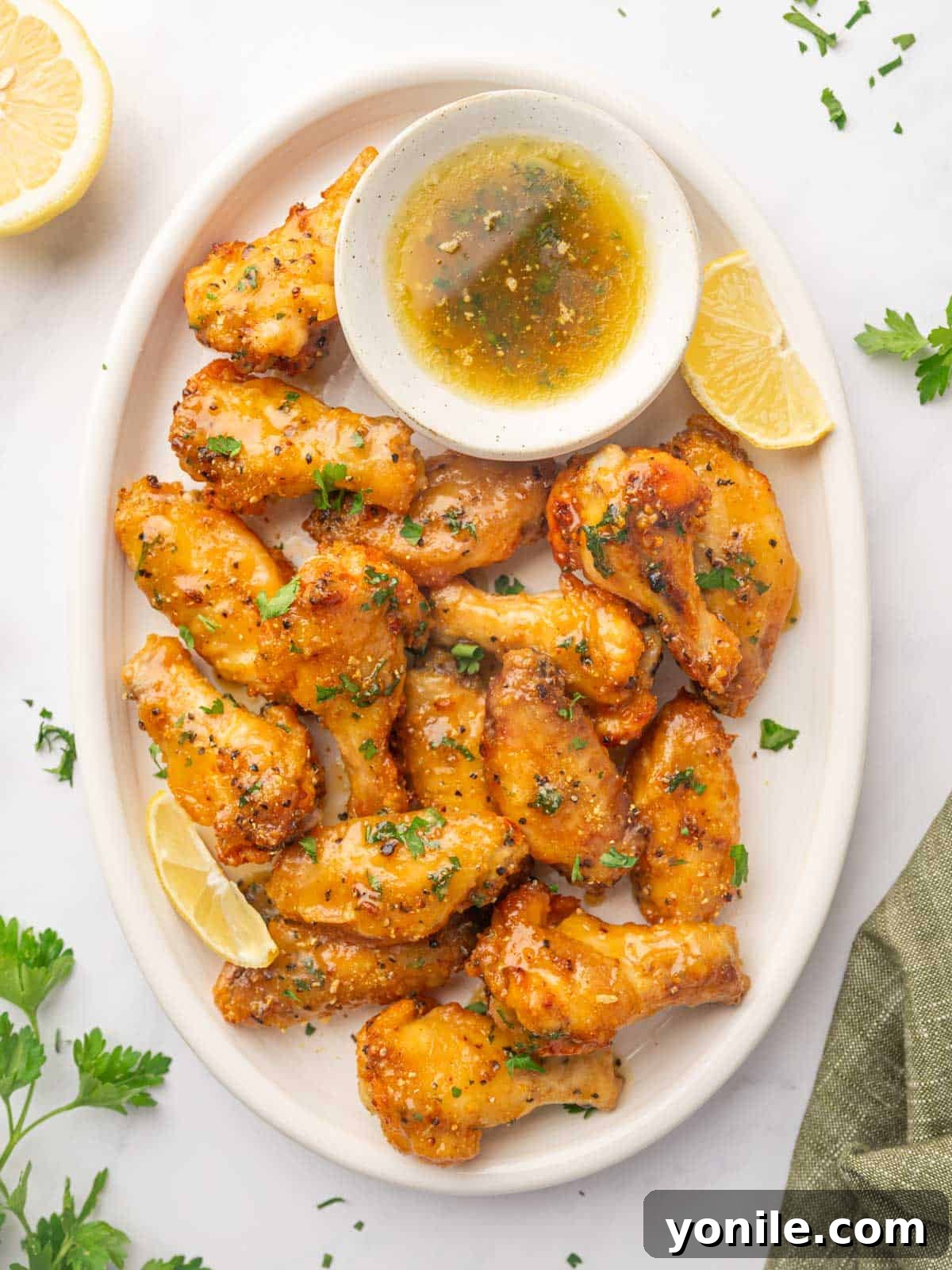 A beautifully arranged platter of golden-brown Honey Lemon Pepper Wings, garnished with fresh parsley and lemon wedges.