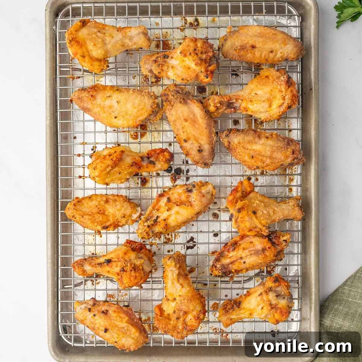 Baked honey lemon pepper chicken wings resting on a wire rack on a baking sheet, golden and crispy.
