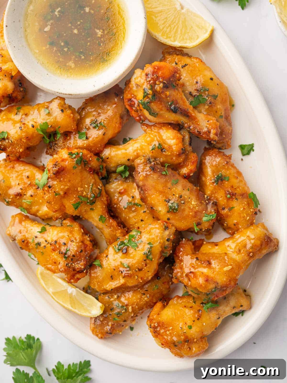 A close-up shot of crispy honey lemon pepper wings on a plate, garnished with fresh parsley.