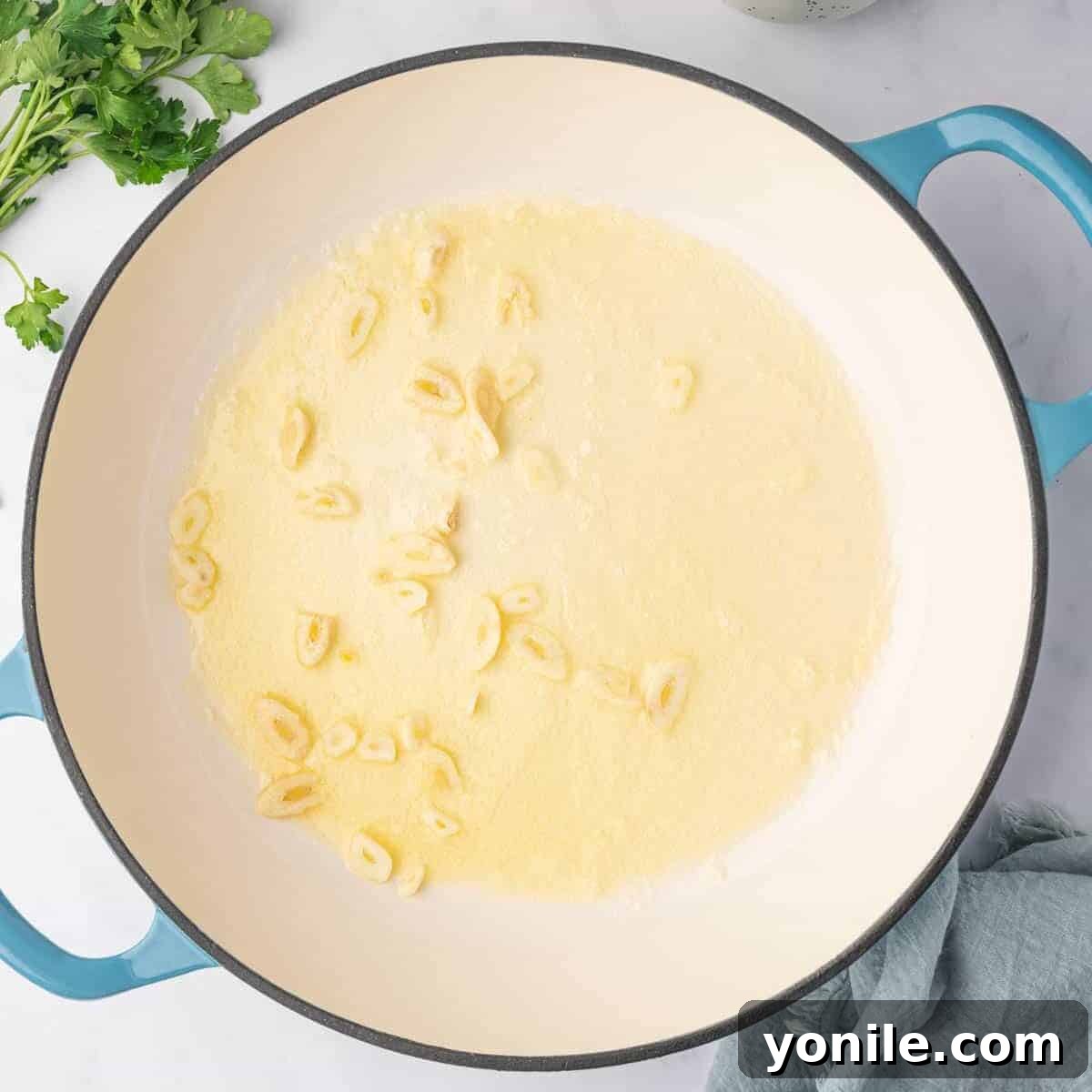 Adding sliced garlic to the cream sauce.