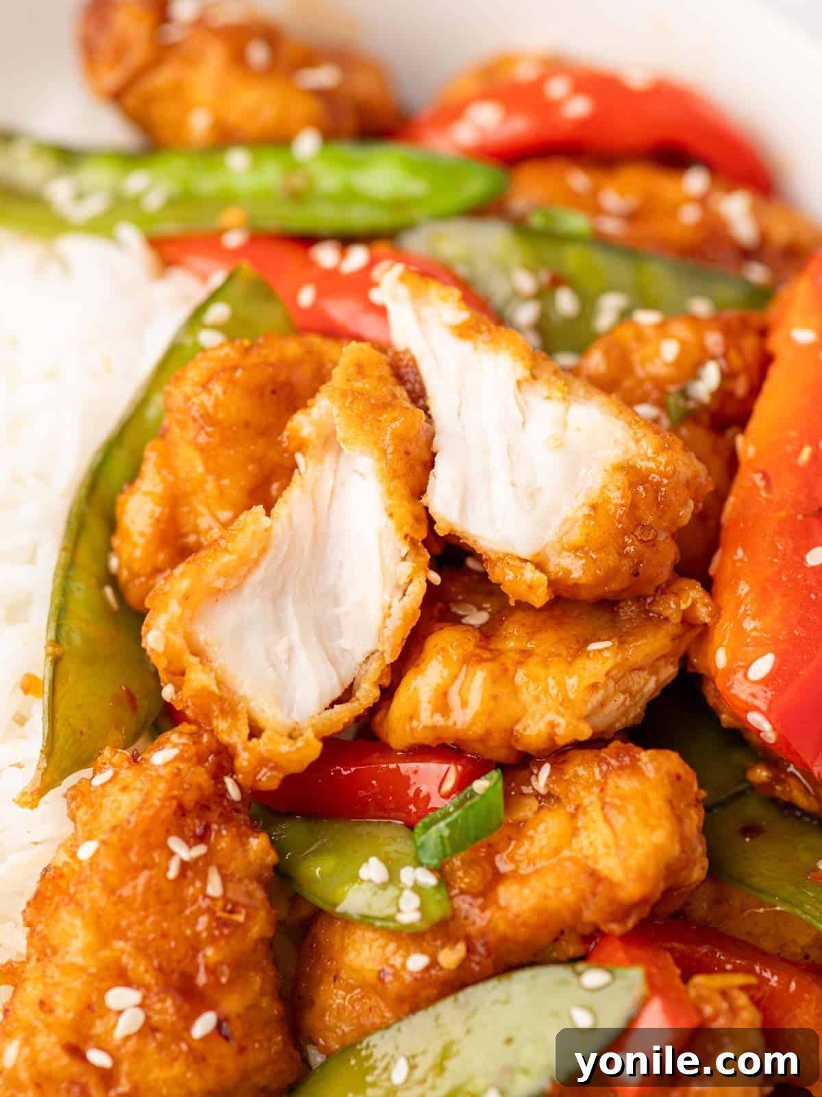 Closeup shot of a piece of crispy honey chili chicken cut in half.