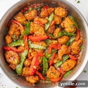 A skillet with sesame seed garnished chicken and vegetables.
