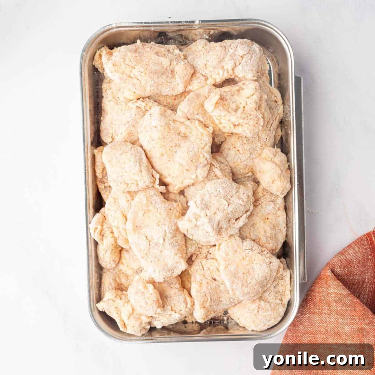 Flour coated chicken breast pieces on a tray.