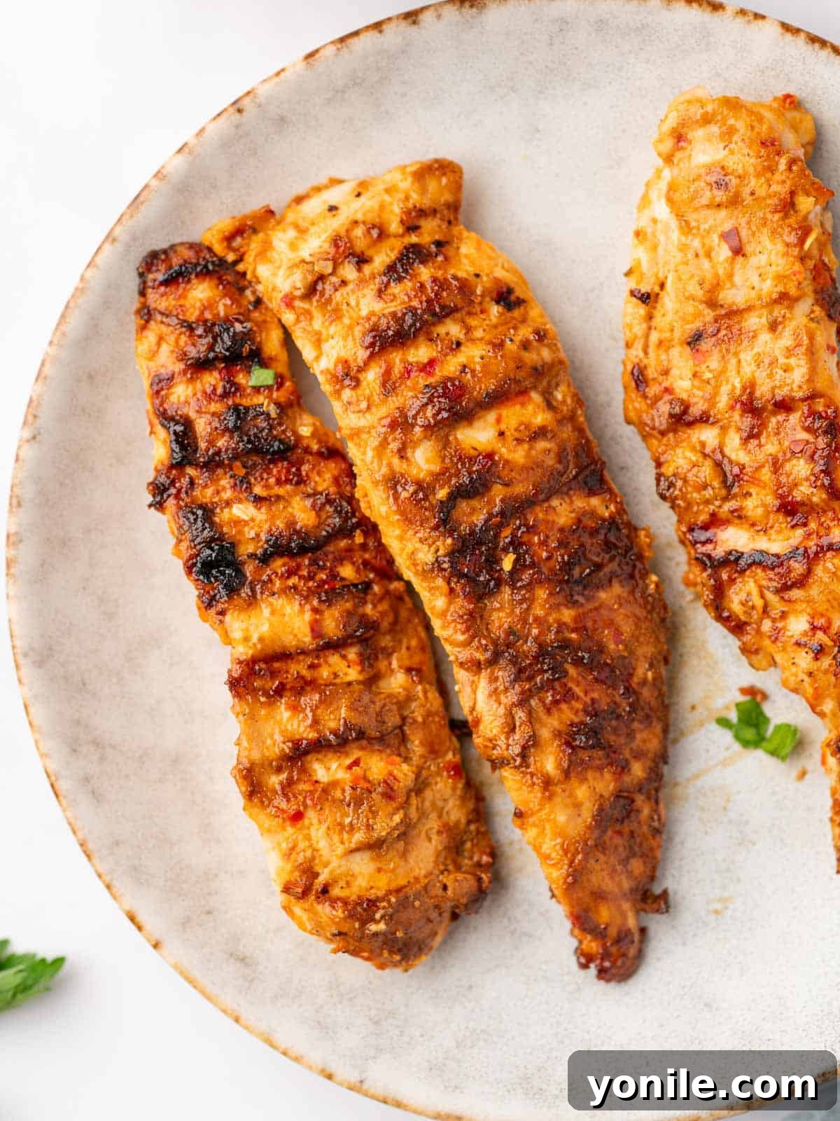 Three peri peri chicken tenders are on a plate.