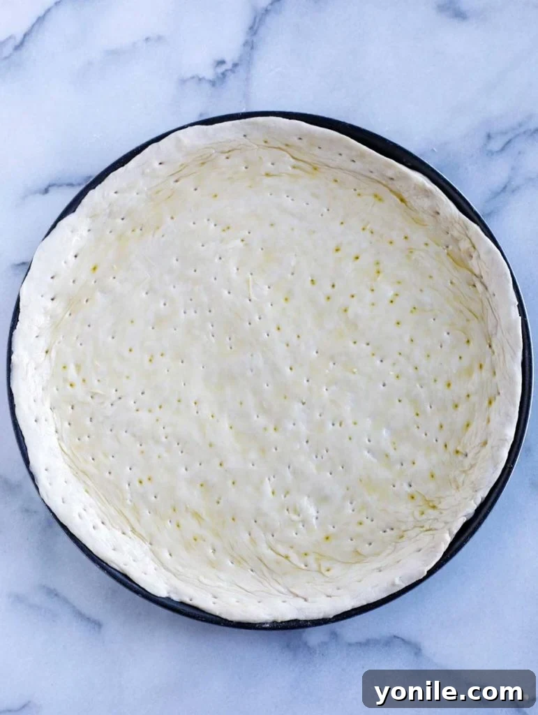 Prepared pizza dough on a pan, ready for its first bake.