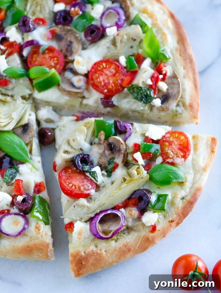 Close up shot of a slice of Mediterranean Veggie Pizza, showing the rich toppings and golden crust.