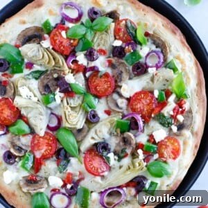 Mediterranean Veggie Pizza with delicious pesto sauce, topped with some alfredo sauce, and packed with fresh veggies and cheese.