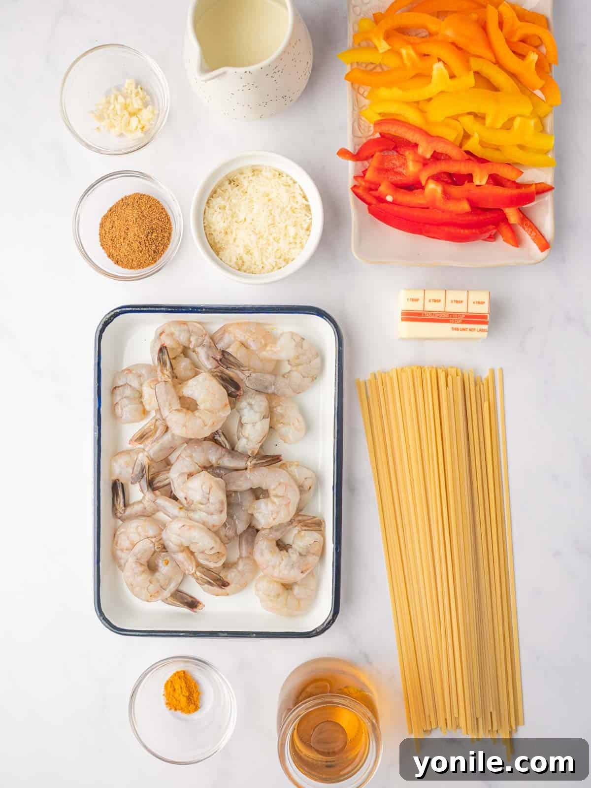 A vibrant selection of fresh ingredients laid out for Jamaican Shrimp Rasta Pasta preparation, including pasta, shrimp, colorful bell peppers, and various seasonings.