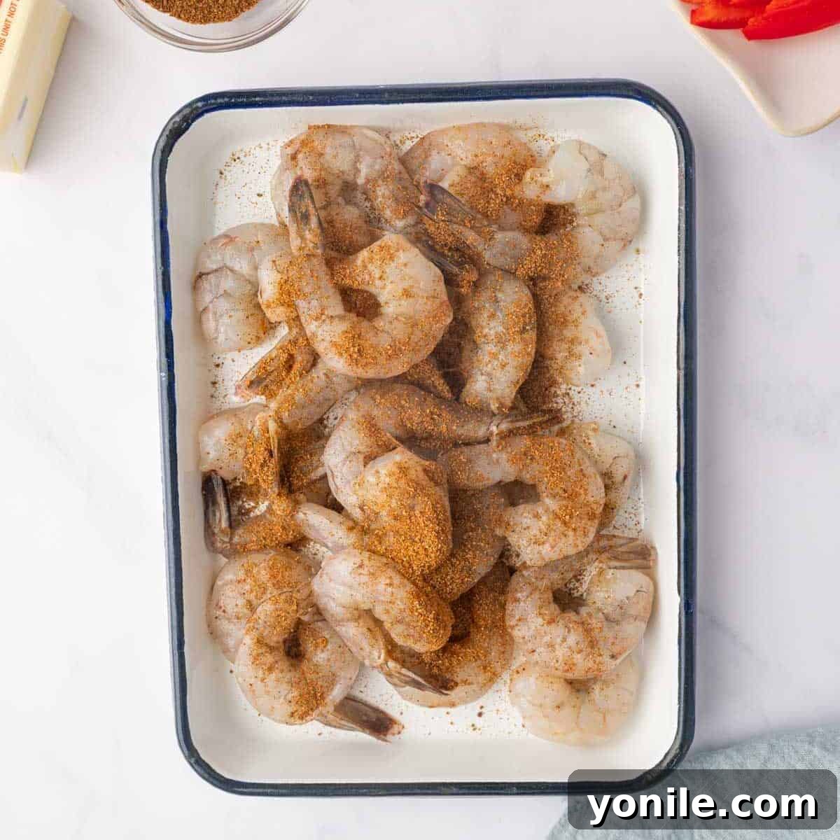 Shrimp is generously seasoned with a rich jerk seasoning blend, ready for cooking.