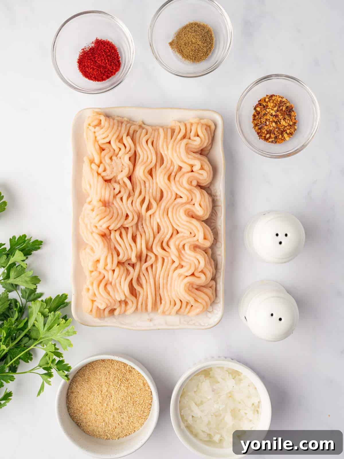 Flavorful Chicken Kofta Skewers 3 A flat lay of fresh ingredients for chicken kofta, including ground chicken, grated onion, bread crumbs, parsley, and a selection of colorful spices.
