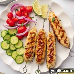 Chicken kofta is served on a plate with fresh vegetables and lime wedges.