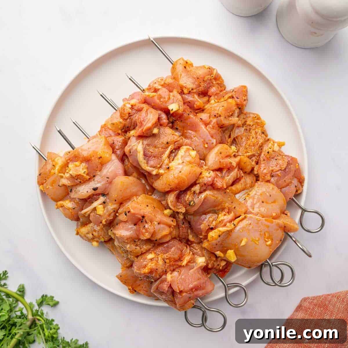 Raw, marinated chicken pieces are expertly threaded onto skewers, ready for grilling.