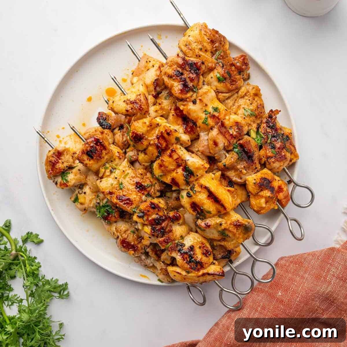 Delicious grilled chicken kabobs arranged on a platter, garnished with fresh herbs and lemon.