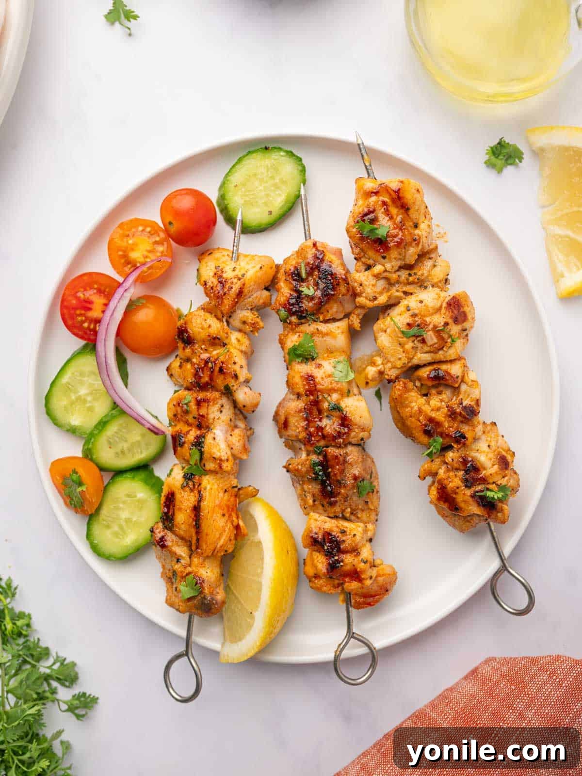 Perfectly grilled lemon pepper chicken skewers neatly arranged on a white plate, ready to be served.