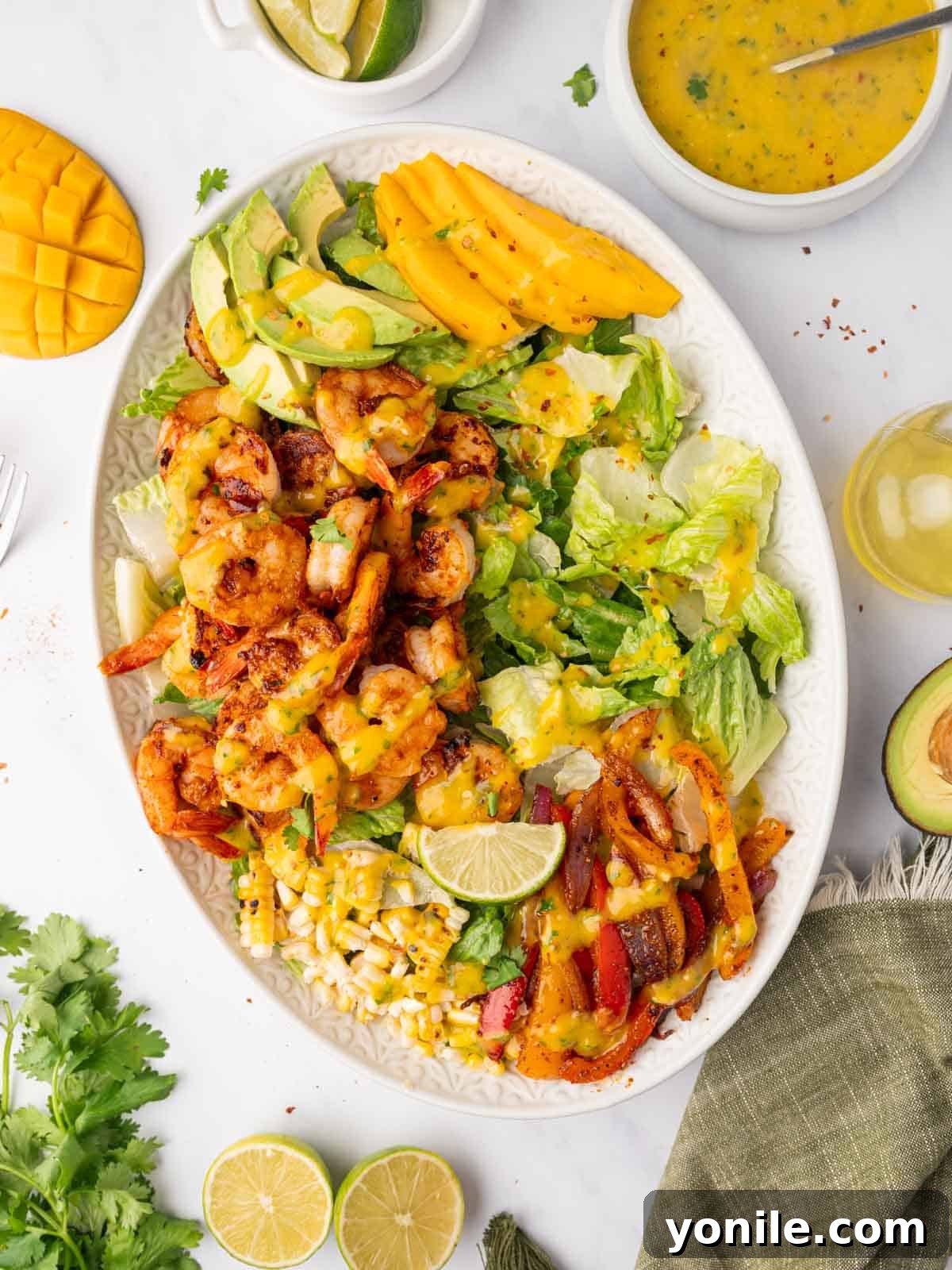 A beautifully arranged Mango Shrimp Salad platter, showcasing grilled shrimp, vibrant mango slices, and fresh greens, all glistening with a zesty dressing.