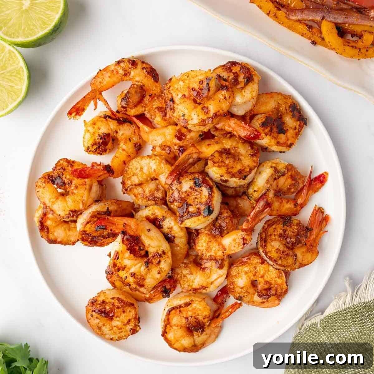 Perfectly grilled shrimp, showing distinct char marks, arranged on a plate.