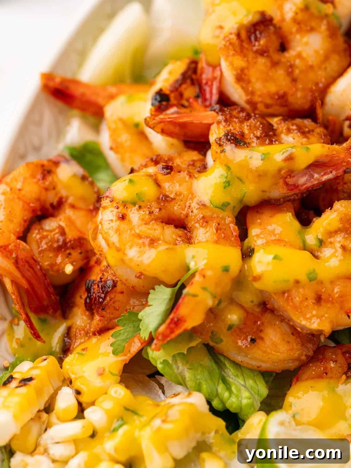 Close-up of perfectly cooked shrimp generously drizzled with the vibrant mango salad dressing.