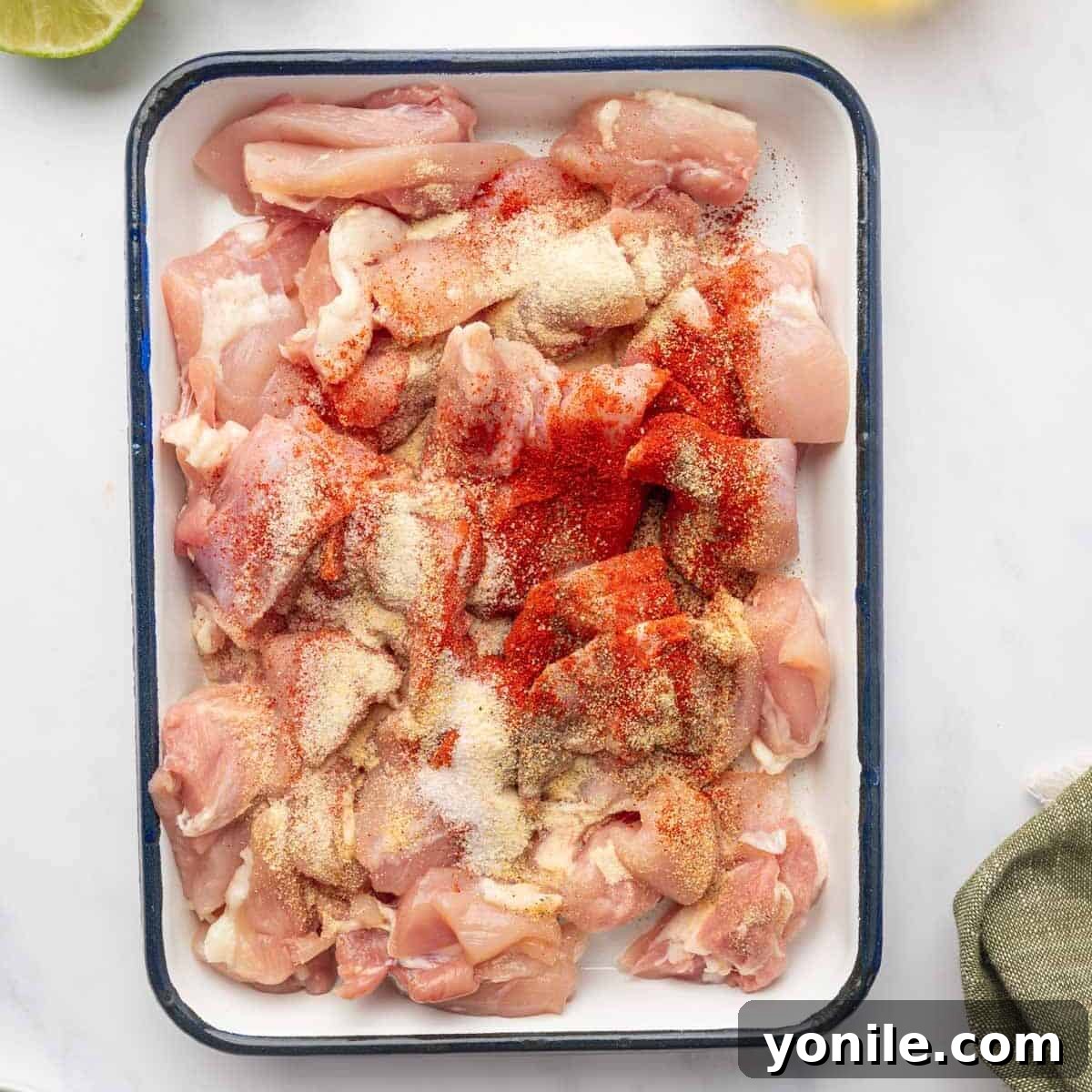 Cubed chicken thighs seasoned generously and ready for marination.