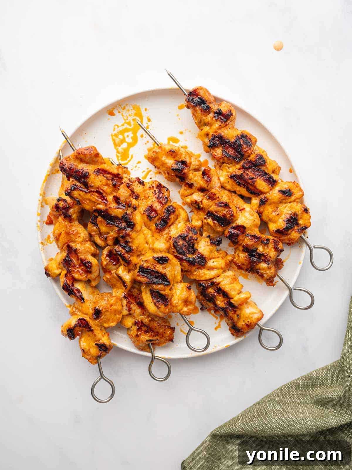 A perfectly grilled Bang Bang Chicken Skewer served on a plate with garnishes.