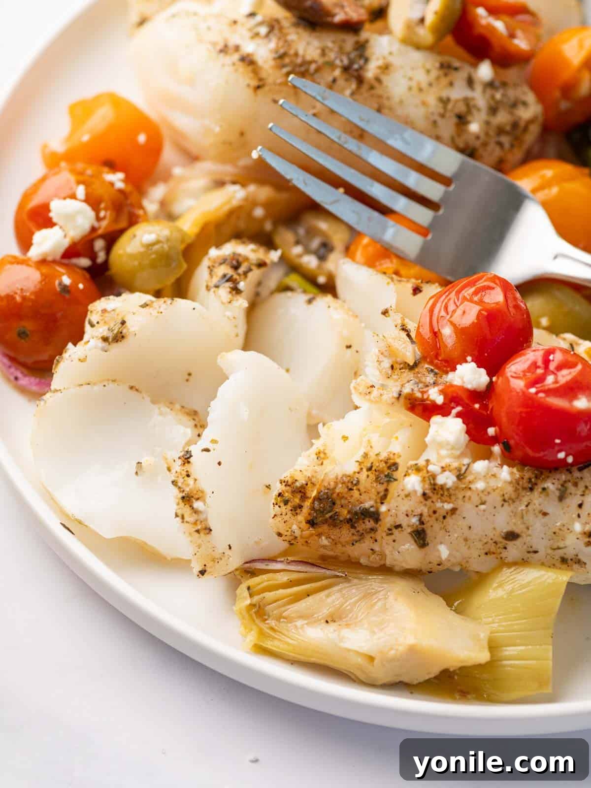 Sun-Kissed Mediterranean Cod 9 A fork gently flakes a piece of baked Mediterranean cod, showing its tender, moist texture.