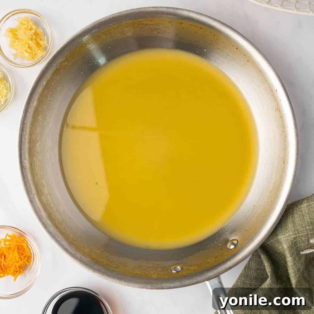 Orange chicken sauce ingredients are combined in a small skillet on the stovetop.