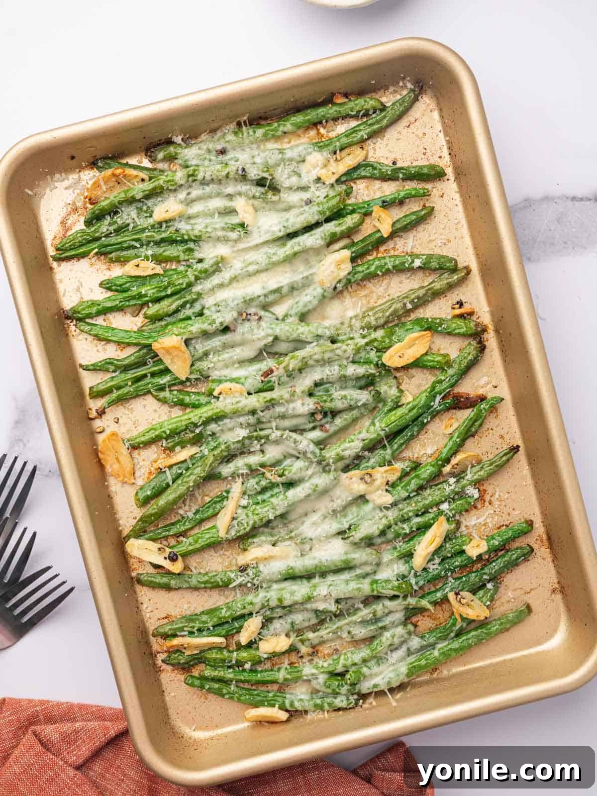 Garlic Parmesan Green Beans topped with melted cheese on a metal baking tray, ready to serve.