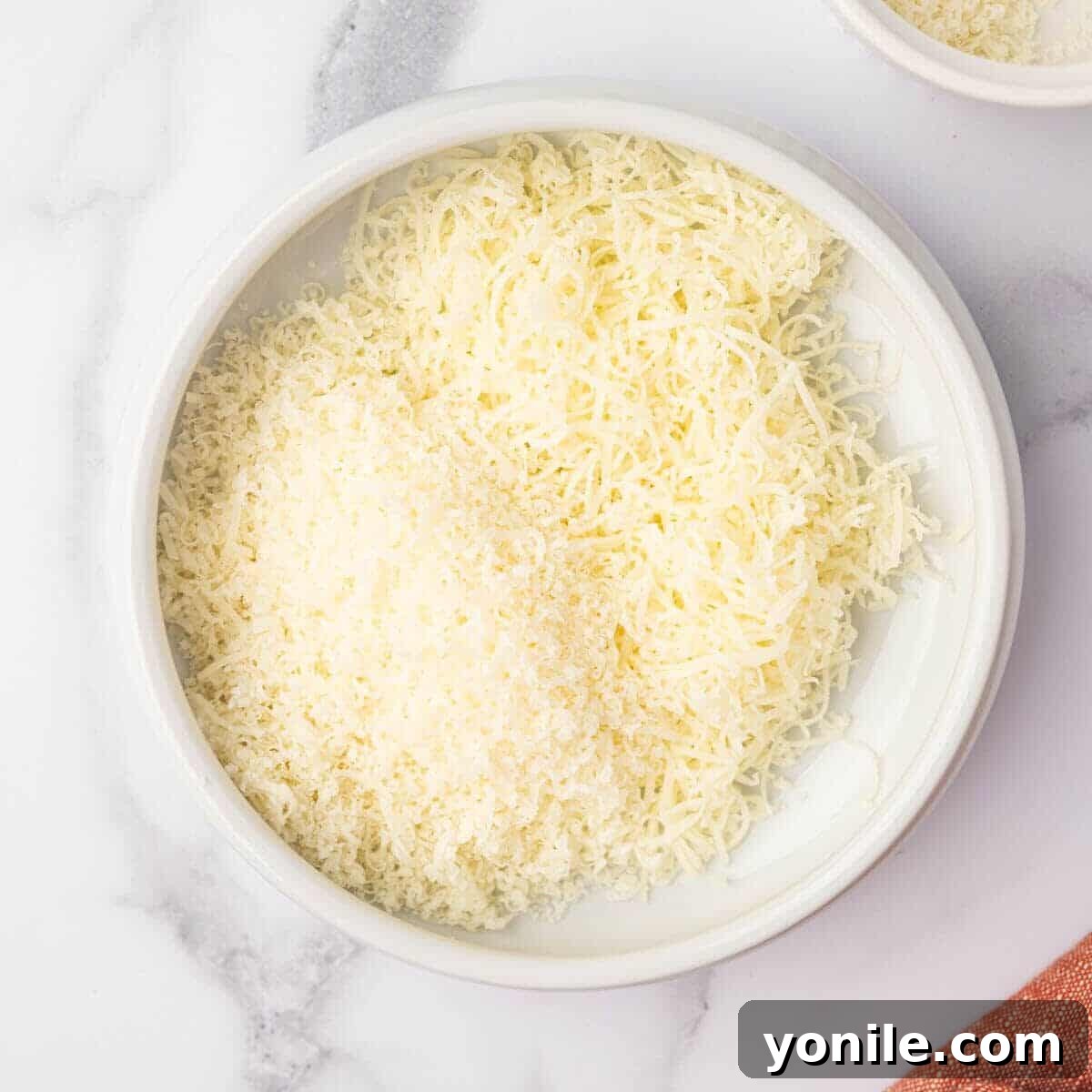 A bowl of freshly shredded parmesan and mozzarella cheese.