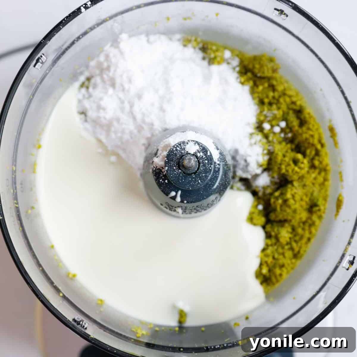 Semi ground pistachio in a food processor along with white chocolate and powdered sugar.