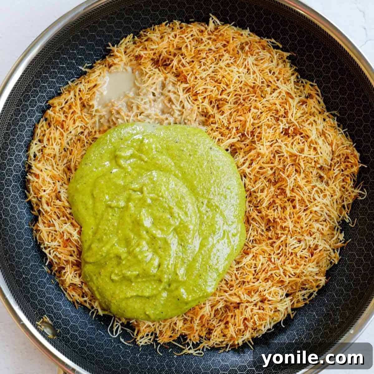 Emirate's Indulgence Bar 5 Adding pistachio cream and tahini to the perfectly toasted kataifi crisp in a pan.