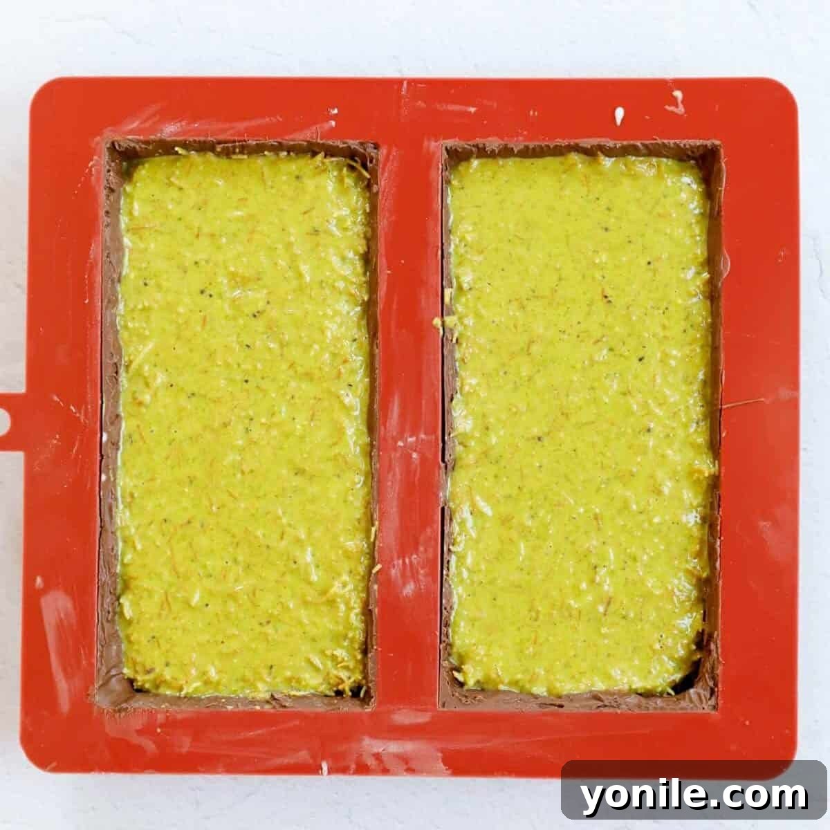 Emirate's Indulgence Bar 9 Process shot illustrating the addition of the pistachio cream kunafa filling into the chocolate mold.