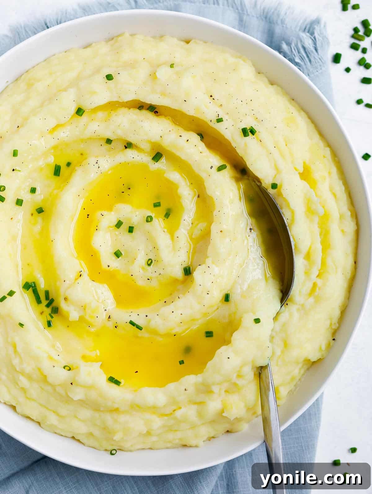 mashed potatoes creamy mashed potatoes in a white plate topped with melted butter and chives, with a spoon in the plate