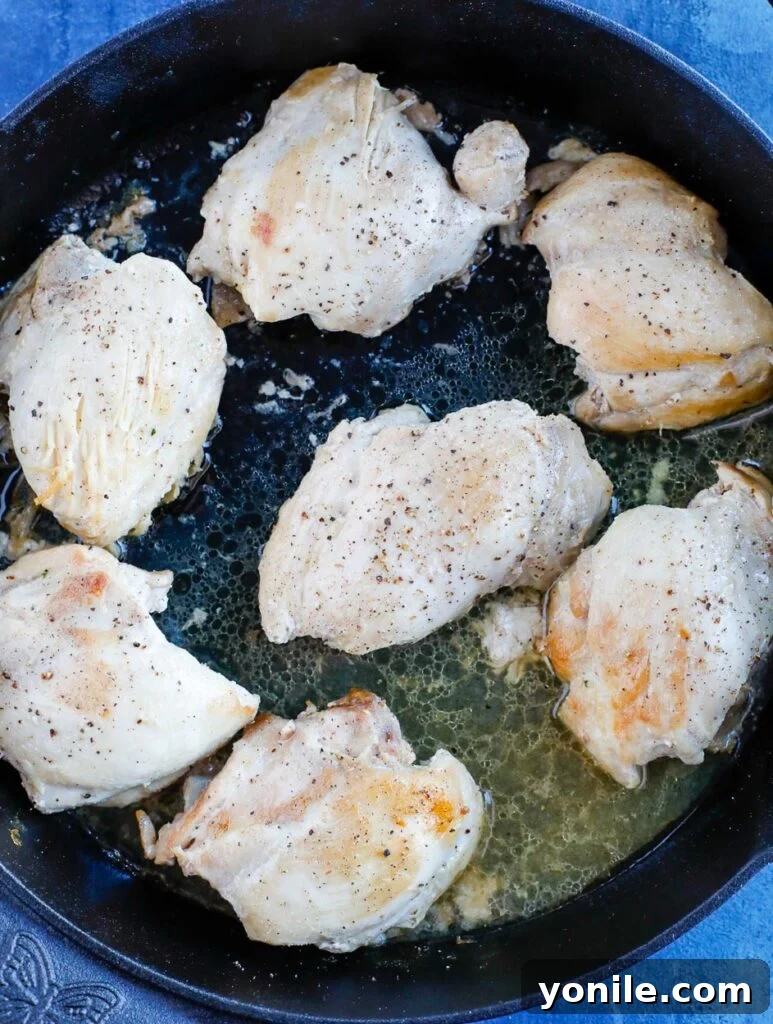 Pan seared chicken thighs in a skillet, turning golden brown