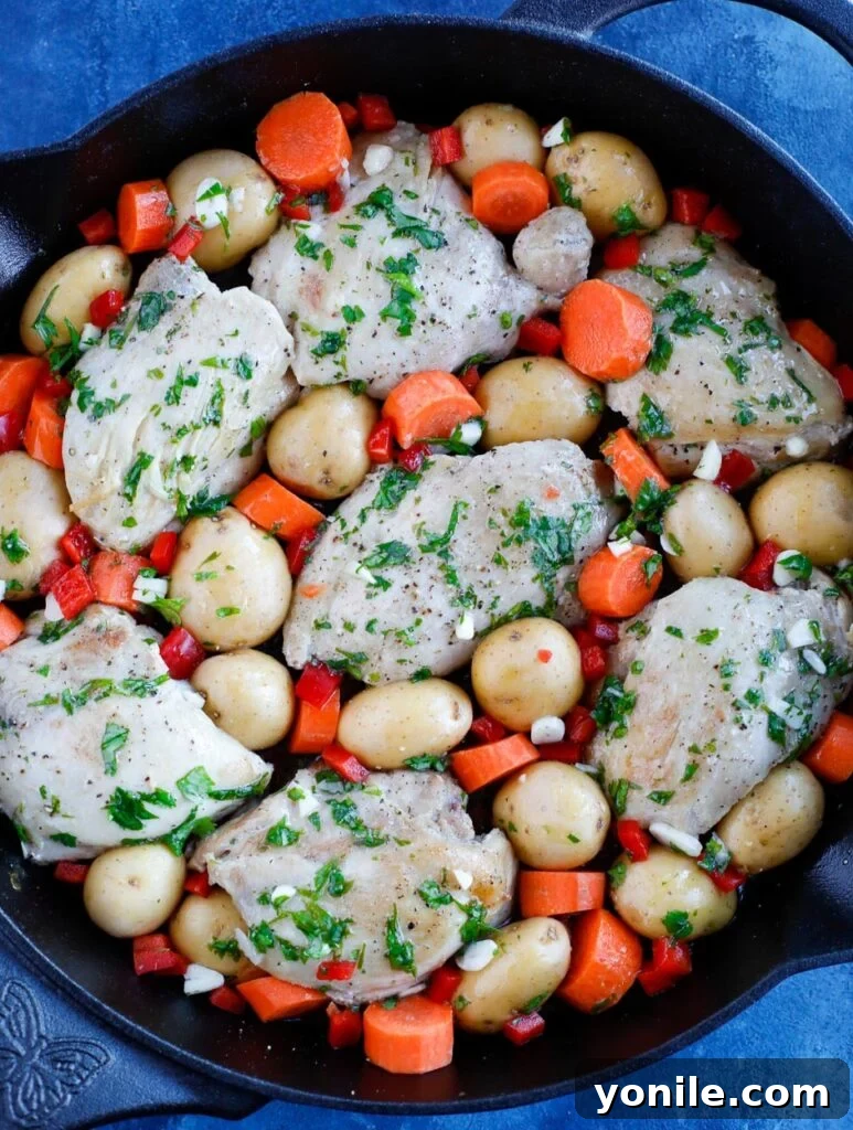 Top-down shot of seared chicken and chopped vegetables in a skillet with marinade