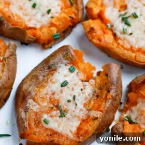 Overhead shot of crispy Smashed Sweet Potatoes with fresh herbs and garlic, garnished with Parmesan cheese, ready to serve.