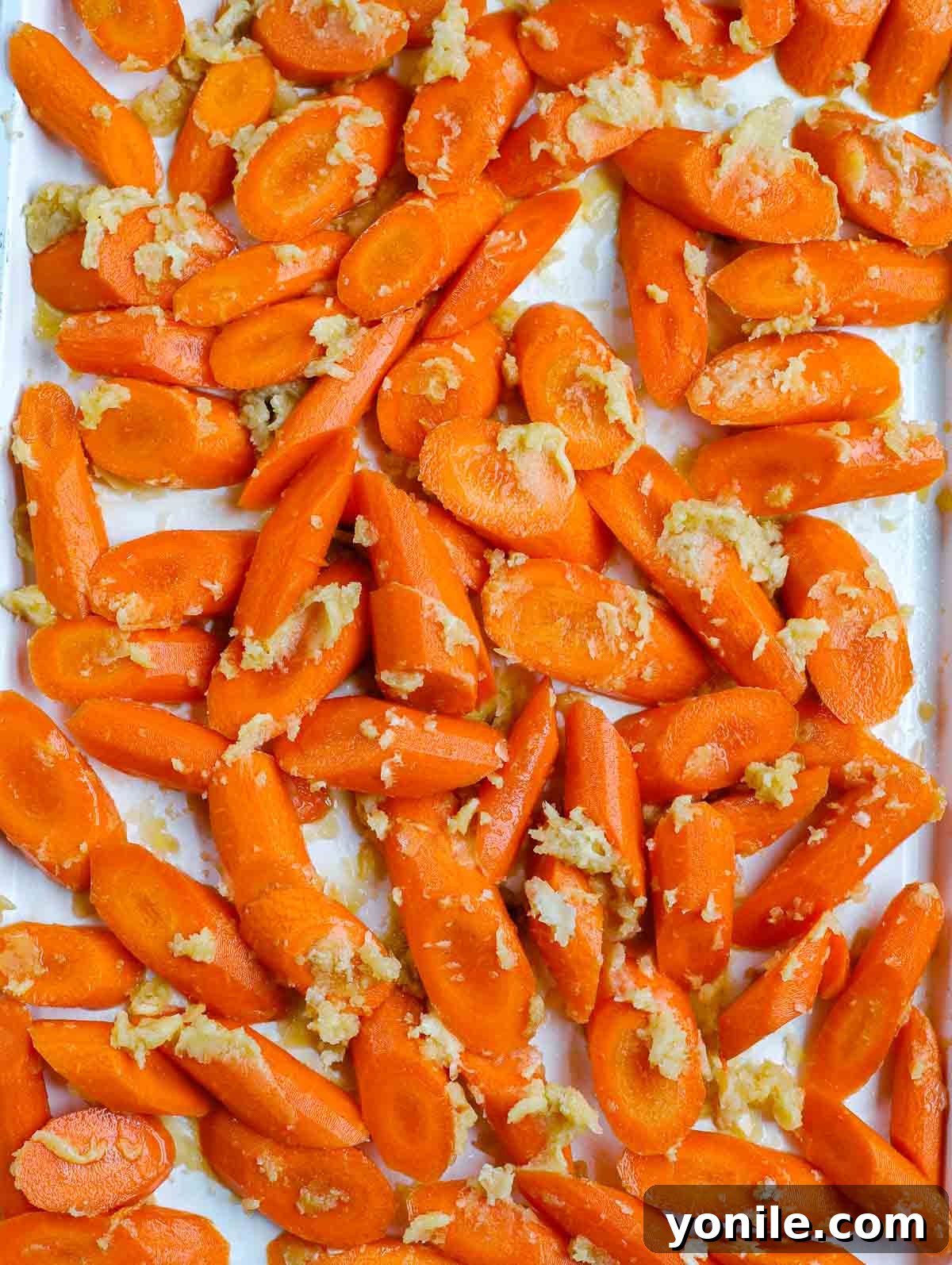 uncooked brown sugar glazed carrots spread on a sheet pan, ready for the oven