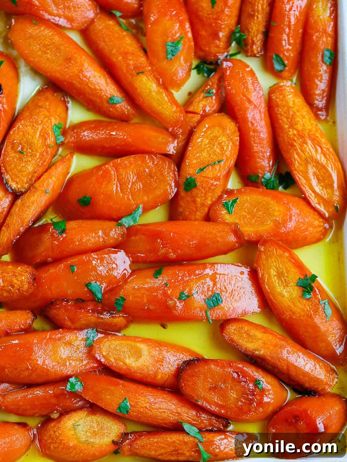 close up shot of the brown sugar glazed carrots on a sheet pan, glistening and perfectly cooked